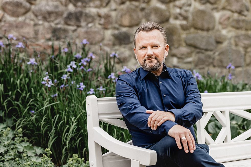 Wolfgang Medger sitzt auf einer weißen Bank.