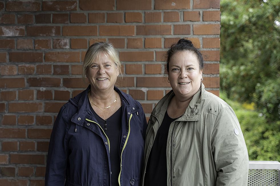 Birgit Fischer (links) und Claudia Hempe lächelnd vor einer Hausmauer.